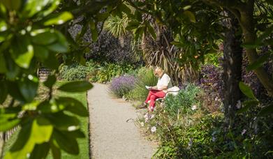 A woman taking a moment to reflect on the bench in Castle Ward's Sunken Garden