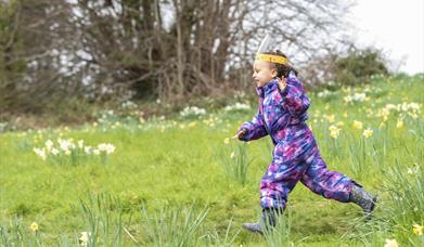 Girl running through meadow wearing easter bunny ears.