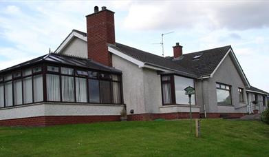 Image shows outside view of the property with sun room