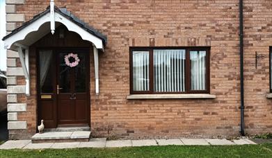 Front exterior of a semi-detached house with a small front lawn.
