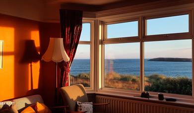 Looking through the front room bay window at a sea view, early in the morning.