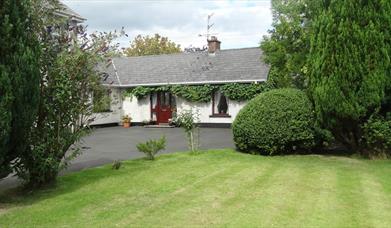 Outside of cottage, garden and trees in image