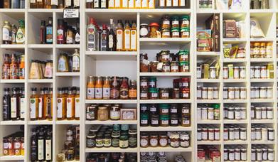 A wall covered with shelves of sauces, spreads and other food products.