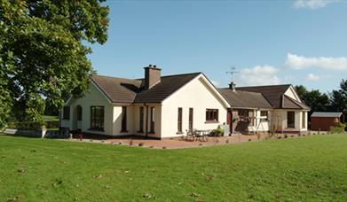 Outside view of house with patio area and large garden