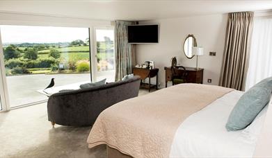 Shows image of double bedroom with large window looking out at countryside view