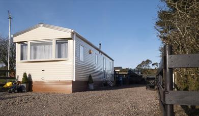 Image of the exterior of a static caravan and a stoned driveway