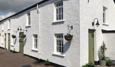 Image shows front of property - whitewashed and with hanging baskets