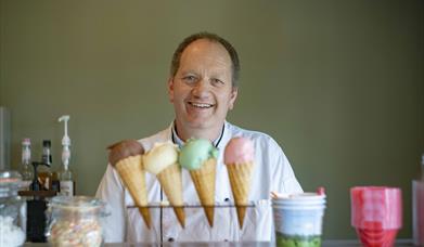 Man smiling standing in front of 4 different ice-creams.