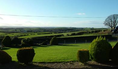 Image shows lawn in front of property with view of the countryside beyond