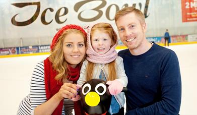 Image is of a couple and small child on the ice rink