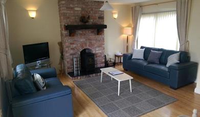 Image shows lounge area with 2 sofas, fireplace and wooden floor