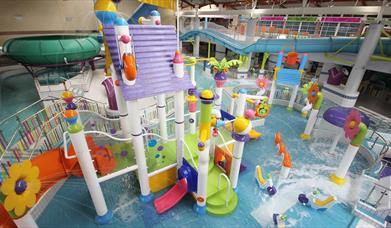 Image shows swimming pool with lots of brightly coloured slides