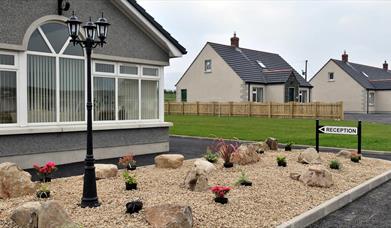 Image shows front of one of the cottages and Reception sign