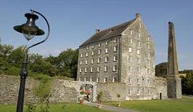 A large seven story 1792 mill with a lamp in the foreground.