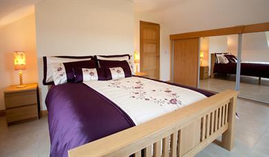 Double bedroom with sliding mirror wardrobe doors, double bed and bedside lockers