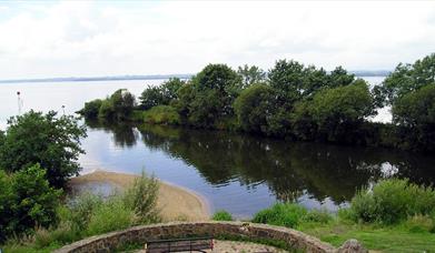 A stone area with a bench with a view at the end of the canal reaching the lough.
