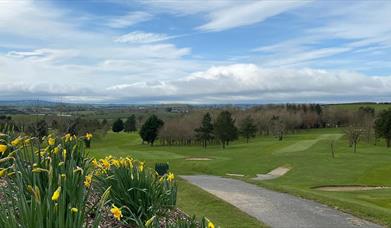 Image shows golf course, walking path and view of countryside beyond