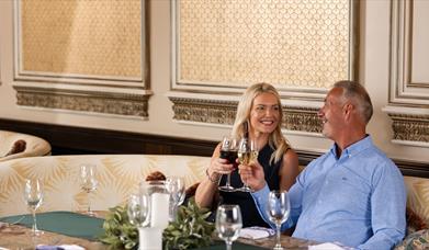 Female and male holding wine glasses at a table in The Gallery of The Old inn