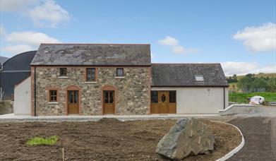 Image shows front of stone built property plus extension