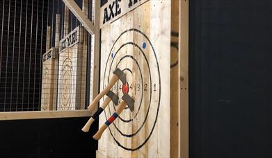 Axes stuck in a wooden target board.