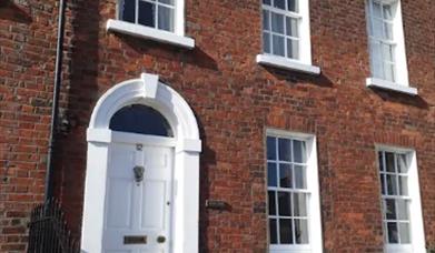 Image shows outside of property which is built in Georgian style with a white front door and sash windows. There are 2 small steps up to front door.