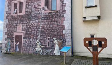 Medieval wall mural in Carrickfergus, with stocks beside it.