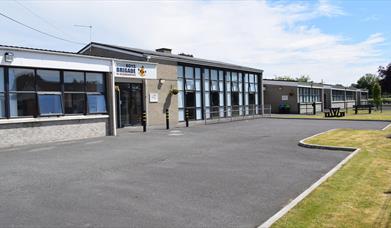 Image is of front of the building with tarmac driveway and grass area beyond