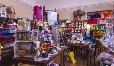 Interior of Lighthouse Yarns with lots of wool displays and people at the crafting table