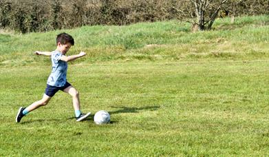 young boys kicks football at Newtownabbey footgolf