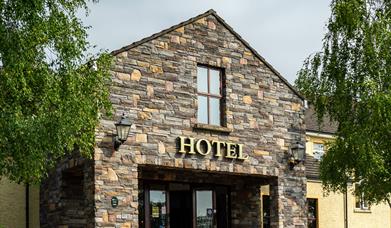 A stone entrance to a hotel with a window and trees.