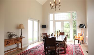 Image shows large dining room with table and 8 chairs. Patio doors onto garden area