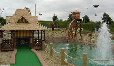 Image shows golf putting area with small lake and fountain