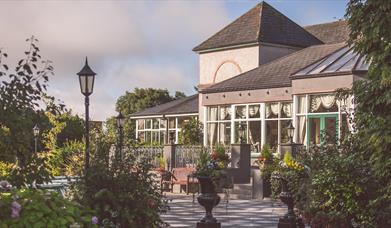 Image of a glass sided building from across a flower and shrub filled courtyard 