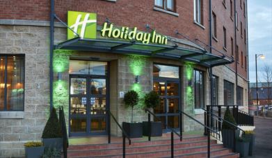 Photo of the entrance of the Holiday Inn Belfast City Centre. Holiday Inn sign above the doors. Stairs and ramp leading to the entrance doors.