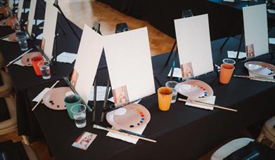 Photo of canvases, paint palettes and glasses of prosecco in the Ulster Museum