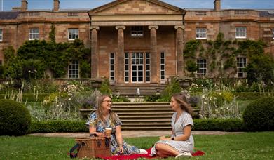 Image is of 2 girls sitting on the lawn at Hillsborough Castle