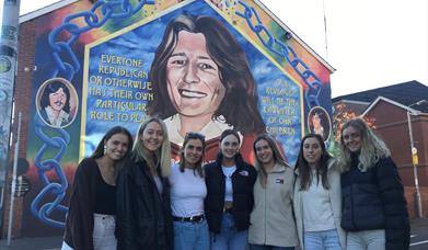 Bobby Sands mural Falls Road Belfast-  Group of visitors standing in front of mural.