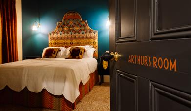 Picture of Arthur's suite inside Arthur's Guesthouse with carefully made double bed and side lamps on the walls