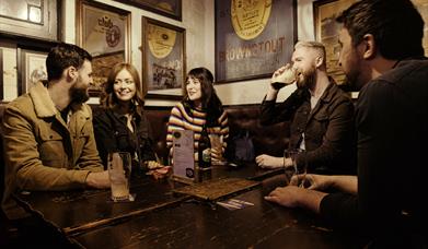 group of people at a table inside the bar chatting and enjoying drinks.