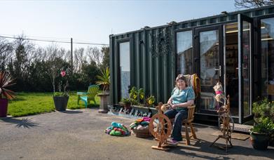 Christine using the spinning wheel outside of the Kiri Cottage Crafts workshop