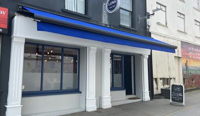 Exterior of Luna Cafe / Bar in Carrickfergus with blue canopy and white pillars