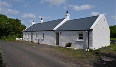 A traditional white country cottage at the roadside.
