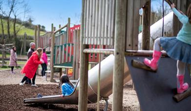 Child climbing and another on a slide in the play park, at Delamont Country Park.