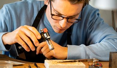 Man making jewellery holding a blowtorch as part of the jewellery making workshop with Gobbins Crafts in Islandmagee