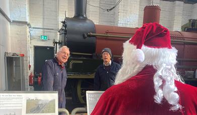 Train with engineers in front of it with Santa looking at them