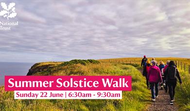 A group walking along the Causeway cliffs at sunrise