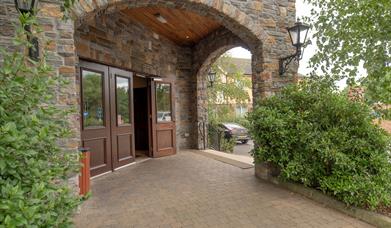 Hotel entrance under stone arches with an exit to a car park.