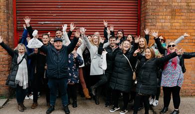 Happy group of guests smiling with their hands in the air of Belfast Food Tour