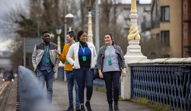 A tour group walking on the Queen's bridge in Belfast.