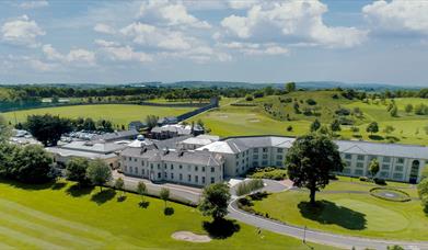 Drone view of the exterior at Roe Park Resort, fluorescent green natural surroundings and golf course.